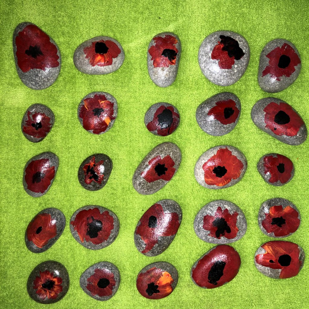 River rocks painted with poppies to observe Remembrance day in Kindergarten.
